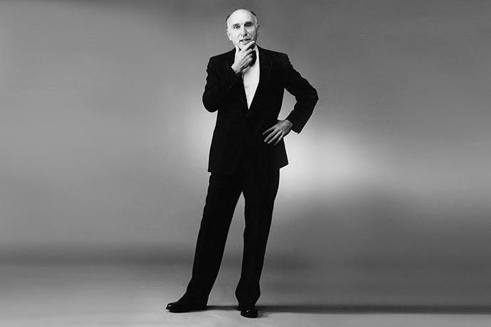 Fashion designer Joseph Ribkoff posing in a black tuxedo